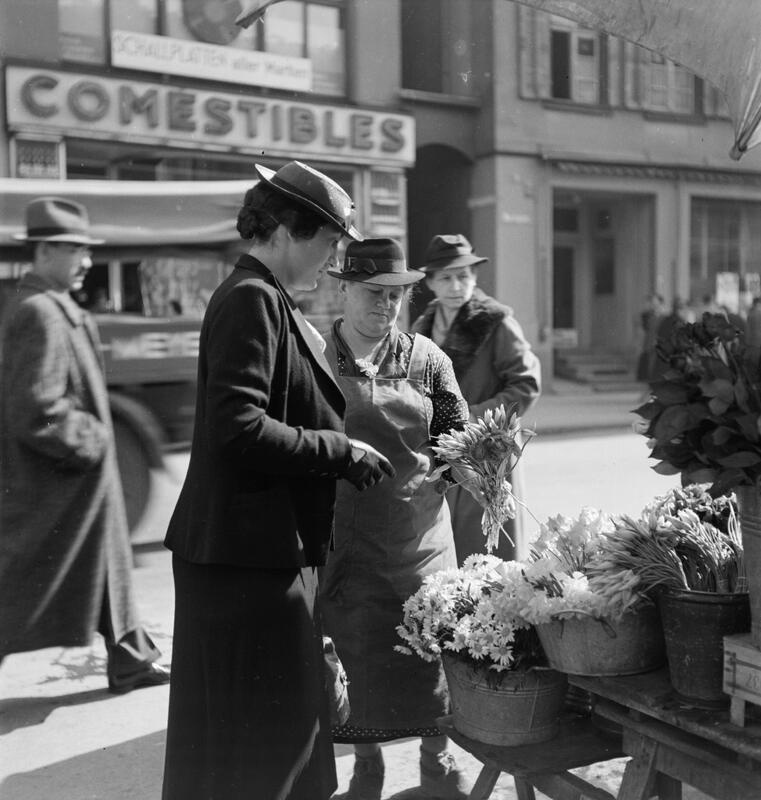 Marktplatz: Marktszene, Frau und Verkäuferin an einem Blumenstand.