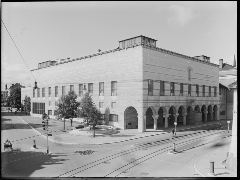 Mehr als dreissig Jahre war umstritten, wo das Basler Kunstmuseum stehen sollte. Schliesslich wurde es 1936 zentrumsnah am St. Alban-Graben eröffnet. Auch seine Architektur gab zu reden, wie es bei vielen Monumentalbauten der Fall war. Zu modern – zu altmodisch – zu bescheiden – zu protzig – zu teuer, so lauteten gängige Einwände. Das Foto zeigt den wenige Jahre alten Museumsbau, aufgenommen während des Zweiten Weltkriegs. Ebenfalls abgelichtet ist die diskrete, aber unverzichtbare Möblierung der Stadt, die sich gerade im Zentrum häuft: Stromleitungen, Tramschienen, Verkehrsinseln, Poller. Ungewöhnlich nimmt sich der Wegweiser aus: Die Richtungsangaben auf seinen Pfeilen waren 1939 entfernt worden, fremden Truppen sollte bei einem allfälligen Einmarsch die Orientierung erschwert werden. Stattdessen leistet der Mast andere, ebenfalls kriegsbedingte Dienste: Zuunterst ist der Weg zum nächsten Luftschutzkeller angezeig