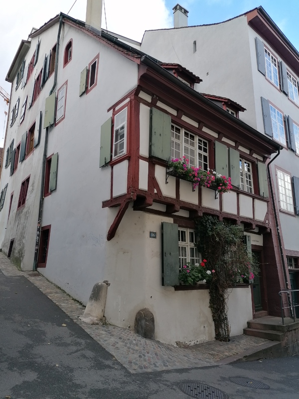 Auch im 15. Jahrhundert wurden in Basel noch Häuser gebaut, die nahezu vollständig Holzkonstruktionen waren. Dazu gehört dieses am Rheinsprung gelegene kleine Haus unterhalb der Martinskirche. Es diente zunächst als Wohnhaus für einen Kirchenkaplan. Kapläne, meist mit dem Dienst an einem Nebenaltar betraut, hatten in etwa so hohe Einkünfte wie gut ausgebildete Handwerker und rangierten in der Mitte kirchlicher Positionen. Der Grundriss des Obergeschosses wurde in typischer Weise durch eine Auskragung vergrößert (KDS BS, Bd. 7, S. 358).