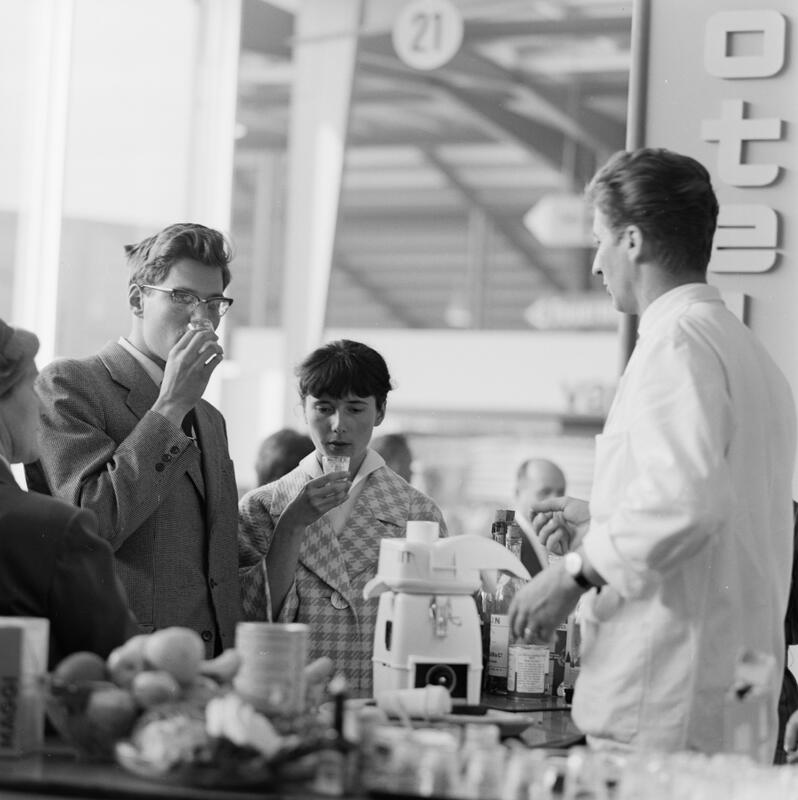 Mustermesse Basel (Muba): Besucher degustieren Saft an einem Messestand.