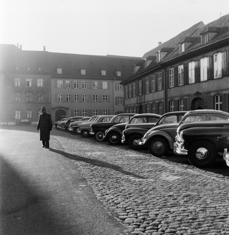 Strassenszene: Geparkte Autos auf dem Münsterplatz, davor ein Polizist.