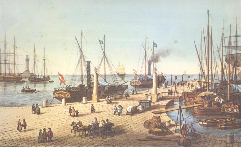 Das Bild zeigt den 1754 gebauten Pier ‹Molo San Carlo›. Im Hintergrund links ist der 1833 in Betrieb genommene Leuchtturm ‹Lanterna› des Freihafens Triest zu sehen, der zu den italienischen Besitzungen des Kaisertums Österreich gehörte. Von Triest aus führten Fernstrassen nach Mitteleuropa. Neben den Dampfschiffen laden und entladen immer noch Segelschiffe ihre Waren. Die Kleidung der Männer auf dem Pier und dem Schiff unten rechts weisen auf Handelsbeziehungen zum Osmanischen Reich hin.