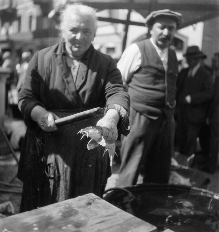 Fischmarkt: Fischverkäuferin mit Barbe und Totschläger in der Hand.