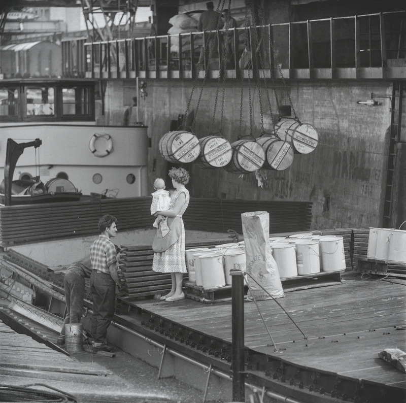 Der Hafen mit den Schiffen, den Ladevorrichtungen und den Menschen wurde vielfach abgelichtet. Auf den Schiffen wohnten nebst den Schiffern auch deren Familien. Die Schifferfrauen beim Aufhängen der Wäsche oder mit Kindern waren ein beliebtes Sujet. Hans Bertolfs Bild erzählt von Familien- und Arbeitsalltag zugleich, die im Leben auf dem Fluss nicht voneinander zu trennen waren.